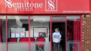 Person standing at an open door of Semitone Studios, a music studio